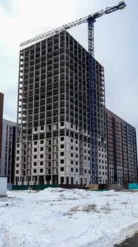 High rise building under construction with crane in snowy urban landscape d.. Stock Photos