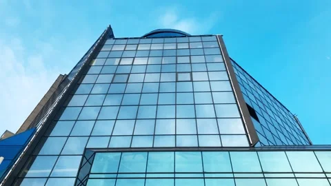 High-rise building windows reflect fast moving clouds and blue sky Stock Footage 244026474