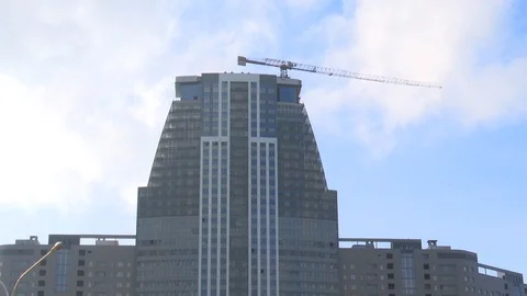 High-rise construction, the tower crane builds a skyscraper on a background Stock Footage 125366023