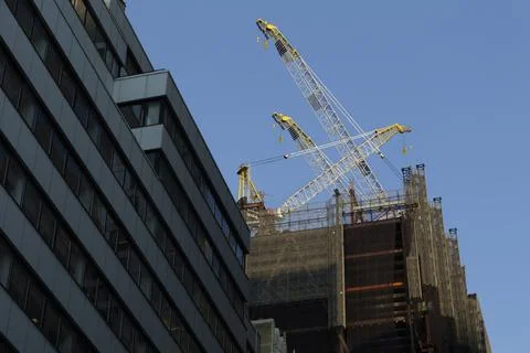 High-rise construction tower crane against the backdrop of a beautiful blue sky Stock Photos