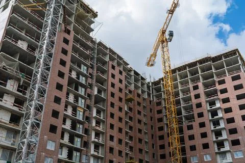High rise residential complex grows under tower cranes with brick facade, ope Stock Photos