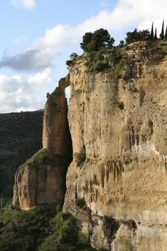 High rock face with small connection through natural bridge to rock pillar Stock Photos