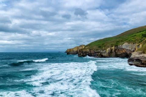 High sandy cliff and waves of Pacific ocean at Tunnel beach, New Zealand Stock Photos