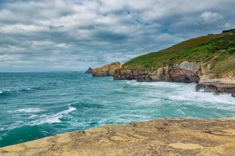 High sandy cliffs and waves of Pacific ocean at Tunnel beach, New Zealand Stock Photos