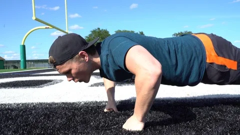 High School athlete doing push ups on foortball field endzone 4k Stock Footage 107453934