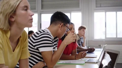 High school classroom: A boy and girl using a laptop computer while attending to Stock Footage 202190641