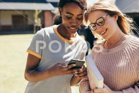 High school girls at college campus with smart phone Stock Photos