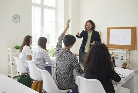 High school student boy raises his hand to ask the teacher a question during Stock Photos