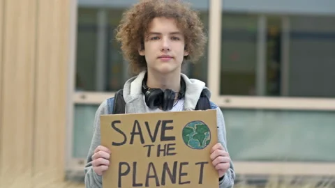 High school student guy holding a poster SAVING THE PLANET. The younger Stock Footage 220263486