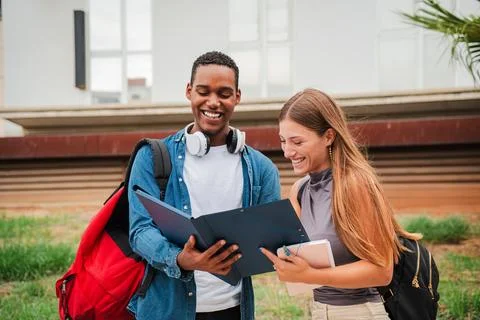 High school student guy smiling while showing his female colleague the homeworks Stock Photos