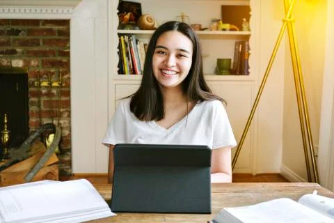 High school student smiles while learning from home with a tablet during pand Stock Photos