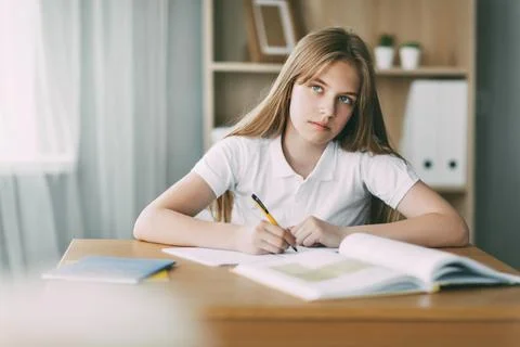 A high school student takes notes from a book, a teenage girl does her homework Stock Photos