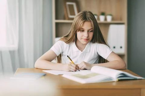 A high school student takes notes from a book, a teenage girl does her homework Stock Photos