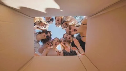 High school students in awe of the items in a cardboard box, experiencing wonder Stock Photos