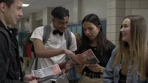 High school students looking at voting brochures in corridor Vidéo 220972327