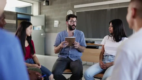 High school tutor and students having class sitting in circle in classroom Stock Footage 242881077