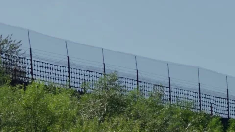 High security border fence with barbed wire on green ridge, tracking shot Stock Footage 340892518