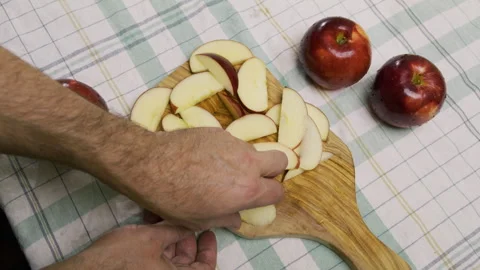 High shot of man's handing taking red apple slices on wooden cutting board Stock Footage 341236995