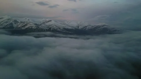 High snowy mountains covered with dense haze, blue sky with clouds at dawn. Video stock 253873752