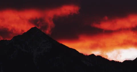 High snowy peak surrounded by blazing orange clouds Stock Footage 63080488
