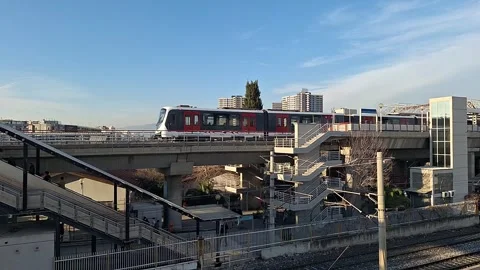 High-Speed Commuter Train Passing Urban Station Platform Stock Footage 329748814