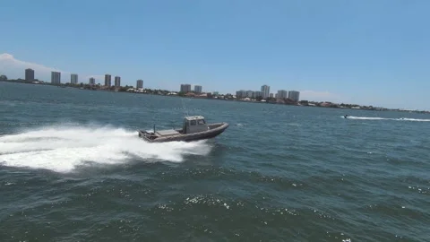 High-speed grey rigid inflatable boat cruising near coastal skyline 動画素材 327672204