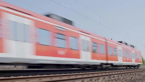 High Speed Orange Commuter Train Passing by Railway Tracks on Sunny Day with Gre Stock Footage 334054974