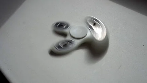 A high speed spinning hand spinner or fidget spinner over the white white Stock Footage 75818378