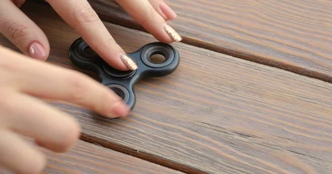 A high speed spinning hand spinner or fidget spinner over the wooden background. Stock Footage 76621798