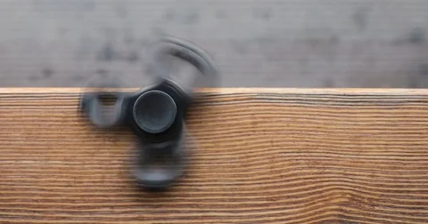 A high speed spinning hand spinner or fidget spinner over the wooden background. Stock Footage 76632915