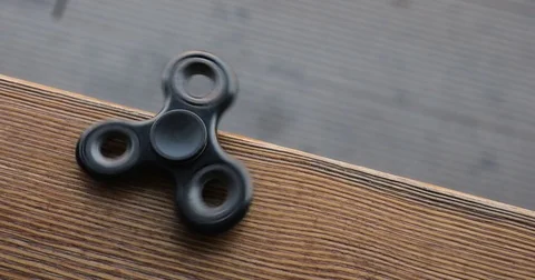 A high speed spinning hand spinner or fidget spinner over the wooden background. Stockbeeldmateriaal 76633443