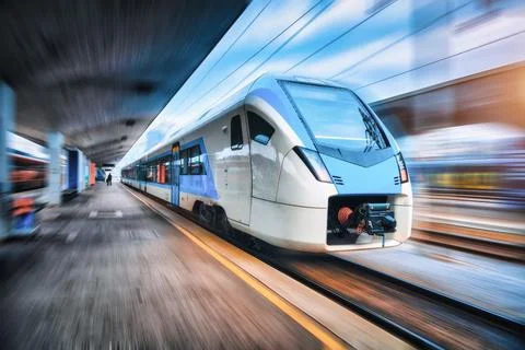 High speed train in motion on the railway station at sunset. Blue modern in.. Stock Photos