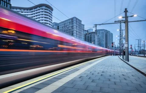 High speed train in motion on the railway station at sunset. Moving red mod.. Stock Photos
