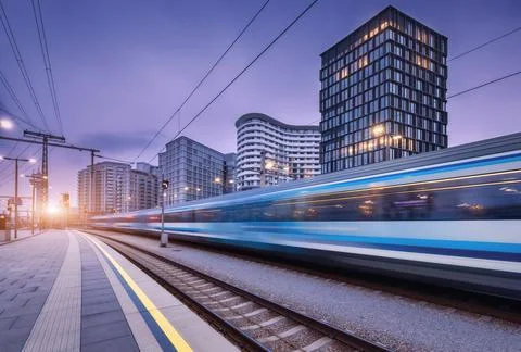 High speed train in motion on the railway station at sunset. Moving blue mo.. Stock Photos