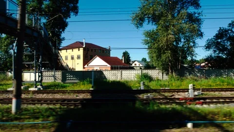 High-speed Train moves past a railway station in a small town in the summer Stock Footage 119355176