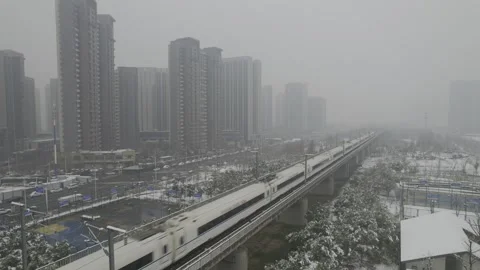 High Speed Train Moving Through Snowy Urban Cityscape Under Elevated Tracks Stockbeeldmateriaal 336545786