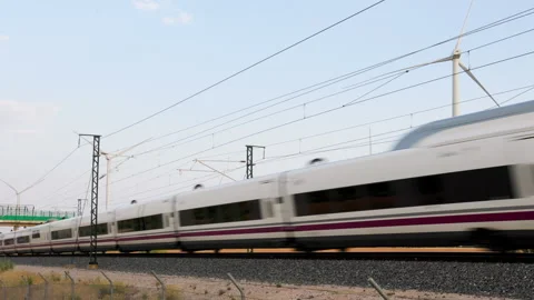 High-speed train passing in front of wind turbines with railway infrastructure Video stock 314834115