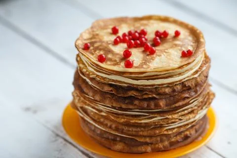 High stack of classic Russian thin pancakes with red currant. Rustic style Stock Photos