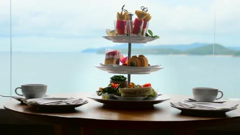 High tea set with assortment of sweets, cakes, sandwiches, fruit canape on table Video stock 194536101