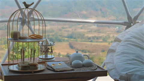 High tea setup with pastries and sandwiches in cozy, scenic dome, Video stock 281011335