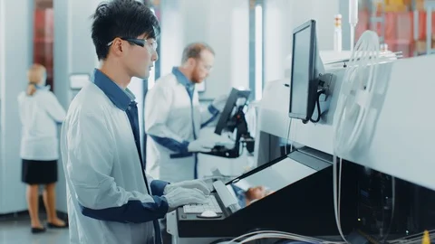 On High Tech Factory Asian Engineer Uses Computer for Programming Robotic Arm Stock Footage 98191161