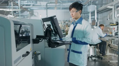 On High Tech Factory Asian Engineer Uses Computer for Programing Machine Stock Footage 98196003