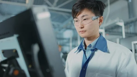 On High Tech Factory Asian Engineer Uses Computer for Programing Machine Stock Footage 98196365