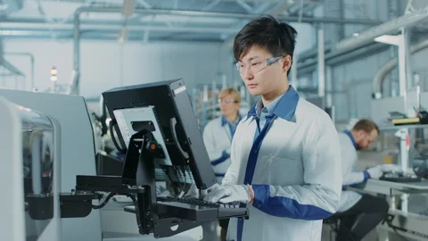 On High Tech Factory Asian Engineer Uses Computer for Programing Machine Stock Footage 98196489