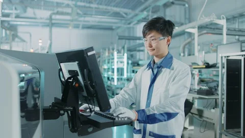 On High Tech Factory Asian Engineer Uses Computer for Programing Pick and Place Stock Footage 98201600