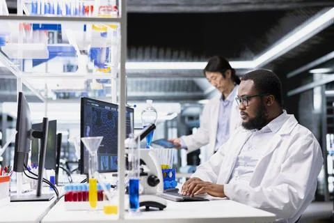 High tech lab technician at desk looking at 3D molecular model Stock Photos