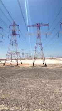 High tension power lines span across desert covered in sand and salt, stretching Stock Photos