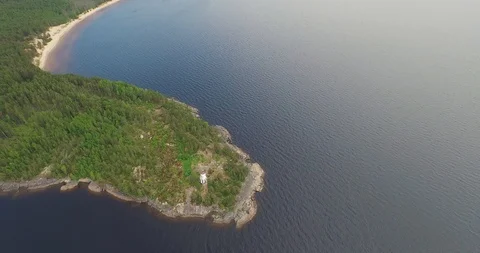 High upper flight over lighthouse on rocky cape among lake  Stock Footage 100981978