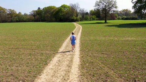 High view following young girl walking along isolated path in fields Stock Footage 108398643