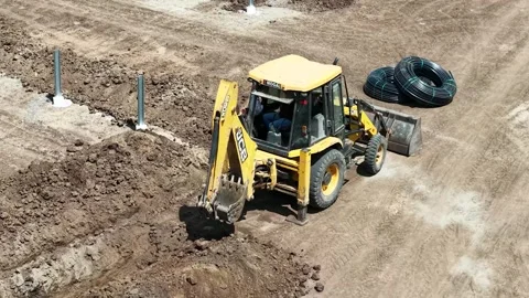 High view framing a yellow industrial backhoe excavator vehicle operating Stock Footage 339912463